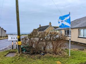 a blue and white sign next to a house at Hamnavoe John o Groats Hostel in John O Groats