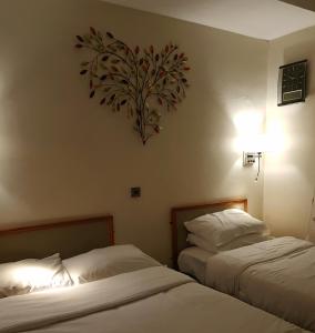 two beds in a hotel room with a heart on the wall at Linden Tree in Gloucester