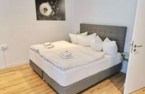 una camera da letto con letto, lenzuola e cuscini bianchi di City Lofts Tegernsee - Moderne Studios zentral gelegen a Bad Wiessee