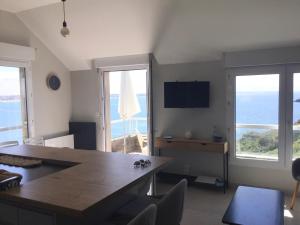 a living room with a table and chairs and windows at Le Cézembre - vue 180 baie St Malo in Saint Malo