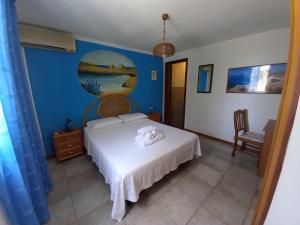 a bedroom with a white bed and a blue wall at Case Pescatori Villette in Lampedusa