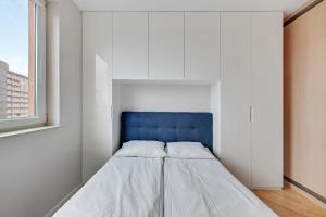 a bed in a white room with a blue headboard at Comfort Apartments Horyzonty in Gdańsk