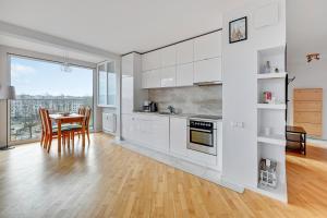 a kitchen with white cabinets and a table with chairs at Comfort Apartments Horyzonty in Gdańsk