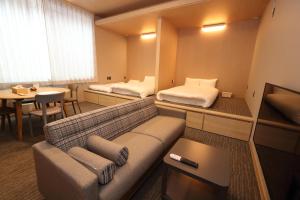 a room with two beds and a couch and a table at White Crystal RoomA in Fukuoka