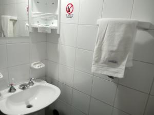 a white bathroom with a sink and a towel at Hostería El Peregrino in Villa Cura Brochero