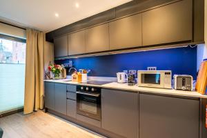 uma cozinha com armários cinzentos e uma parede azul em Bootham Row 1 em York