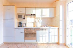 Maashof Schimmelreiter في هوسوم: مطبخ بدولاب بيضاء وموقد