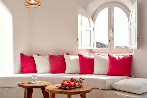 a couch with pink pillows and a bowl of fruit on a table at Finikia Memories Hotel in Oia
