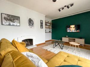 een woonkamer met een gele bank en een groene muur bij Cinéma & Disney avec Balcon & Parking en Hyper Centre in Amiens
