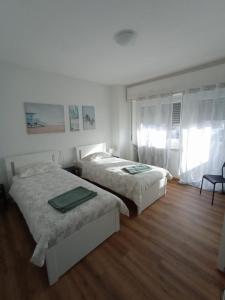twee bedden in een slaapkamer met witte muren en houten vloeren bij Maison al Bivio (Locazione Turistica) in Trichiana