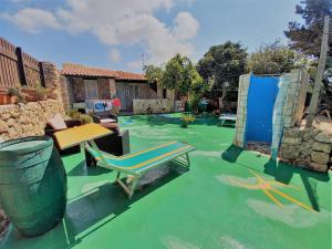 un patio con suelo verde, mesa y banco en Case Pescatori Villette, en Lampedusa