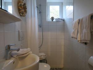 a white bathroom with a sink and a shower at Ferienhaus Süder-Tresker in Tinnum