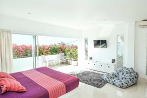 ein weißes Schlafzimmer mit Bett und Balkon in der Unterkunft Rapture Surfcamps Green Bowl in Ungasan