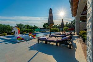 a swimming pool with two tables and an umbrella at Villa Lorema-pet friendly on 5000 sqm garden,pool, jacuzzi, billiard&PS5 in Sveti Filip i Jakov