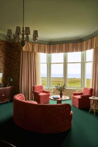 a living room with red chairs and a table and windows at Marine North Berwick in North Berwick