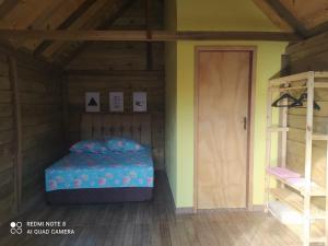 a bedroom with a bed in a room with a door at Chalés Rústicos e Românticos - Na terra das Cachoeiras in Faxinal