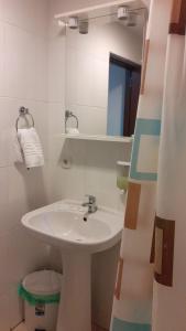 uma casa de banho branca com um lavatório e um espelho em Pensiunea Crin-Tania em Mioveni