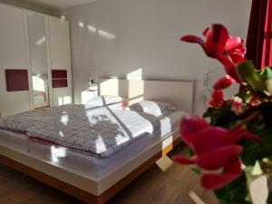 1 dormitorio con 1 cama y una planta con flores rojas en Water Lily Apartment, en Berchtesgaden