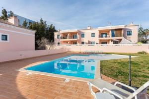 a swimming pool with two chairs and a house at Delfimar Suite Alvor Apartment in Alvor