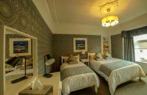 een slaapkamer met 2 bedden en een kroonluchter bij Dana Villa Holiday Accommodation in Oban