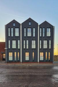 un edificio nero con due finestre in un parcheggio di Schierzicht Logement a Lauwersoog