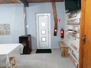 een kamer met een deur, een tafel en een brandblusser bij Casas do Patrao II in Sabugueiro +11 foto's