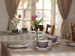 a table with plates and cups and a vase of flowers at La Villa Garenne in Vannes