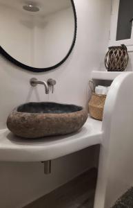 een badkamer met een stenen wastafel en een spiegel bij Konstantza's Superior Suite in Naxos Chora