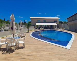 uma piscina com cadeiras e uma mesa com um guarda-sol em Paraiso Barra Hotel em Barra de Santo Antônio