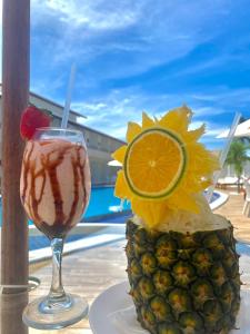 a drink and a pineapple on a table with a view at Paraiso Barra Hotel in Barra de Santo Antônio