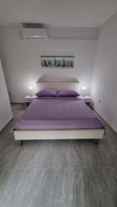 a bedroom with a large bed with purple sheets at Room Airport Split in Kaštela
