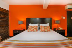 a bedroom with a large bed with an orange wall at Talk of the Town Beach Hotel & Beach Club by GH Hoteles in Oranjestad