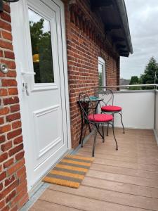 two chairs and a table on a porch with a door at Doddy‘s Stuuv in Niesgrau