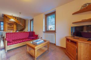 a living room with a red couch and a tv at CHALET PONTAL 5 - Relax e vista sulle montagne - COUR 0145 in Entrèves