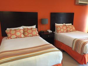 奧倫吉士達的住宿－城鎮講談海灘俱樂部酒店，橙色墙壁的酒店客房内的两张床