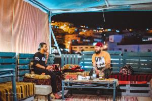 two men sitting under a tent on a roof at Petra Main Gate in Wadi Musa