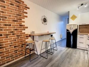 a kitchen with a brick wall and a counter with stools at Le Temps d'une Pause in Bourgoin