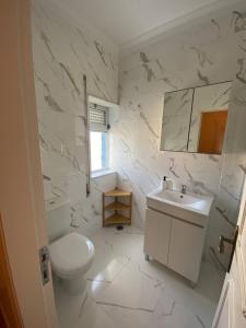 a white bathroom with a toilet and a sink at Zulla House in Nazaré