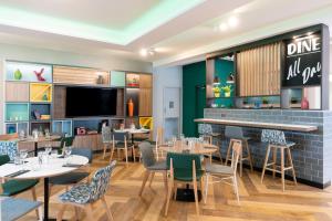 a restaurant with tables and chairs and a bar at Holiday Inn Gloucester - Cheltenham, an IHG Hotel in Gloucester