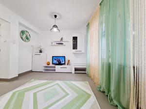sala de estar con cortina verde y TV en Cómodo apartamento cerca del mar en Santa Pola