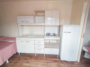 a small kitchen with white cabinets and a white refrigerator at Marco Zero Containers 4 in Balneário Camboriú +4 photos