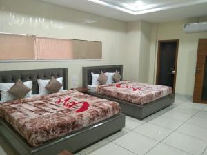 two beds in a hotel room with red sheets at DUDI HOTEL in Bikaner