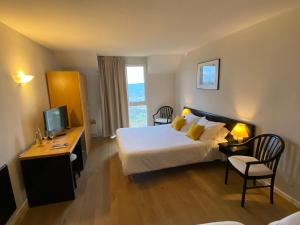 a hotel room with a bed and a desk and a television at Le Relais de Castelnau in Loubressac