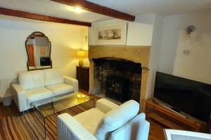 a living room with white furniture and a fireplace at Hope Cottage, Great Longstone in Great Longstone