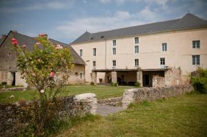 un grand bâtiment avec un mur en pierre et une cour dans l'établissement Gîte des Grands Moulins de Baugé, à Baugé