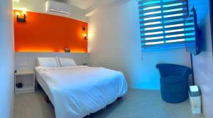 竹山7號民宿 في Kuei-lin-li: غرفة نوم بسرير ابيض وجدار برتقالي