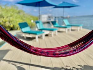 a hammock with chairs and umbrellas on a deck at Vistalmar Ocean Suites in Oranjestad