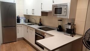 Una cocina con gabinetes blancos y electrodomésticos de acero inoxidable. en Toro 2, 2º en la misma Plaza Mayor de Salamanca, en Salamanca