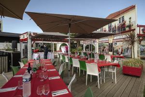 a row of tables and chairs with umbrellas on a deck at Belambra Clubs Seignosse - Les Tuquets in Seignosse