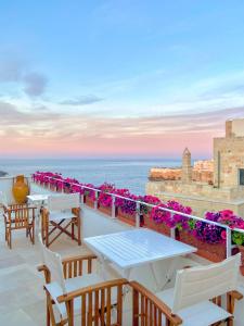 un patio con tavoli, sedie e vista sull'oceano di A Casa di Elena a Polignano a Mare